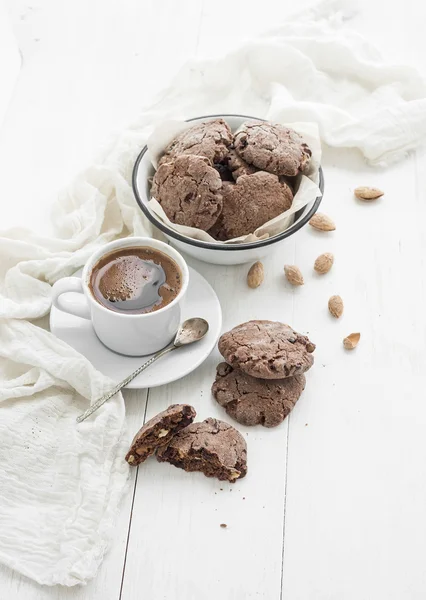 Шоколадное печенье с миндалем и клюквой, чашка кофе, белый деревянный фон — стоковое фото