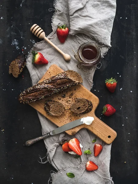 早餐套餐。黑面包吐司与新鲜的草莓、 蜂蜜和马斯卡彭奶酪黑暗 grunge 表表面上 — 图库照片