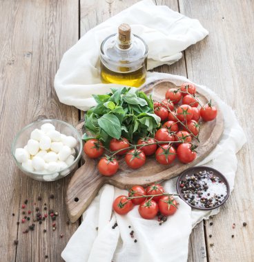 fesleğen, kiraz domates, mozarella, zeytinyağı, tuz, baharat eski ahşap arka plan üzerinde rustik doğrama tahtası üzerinde