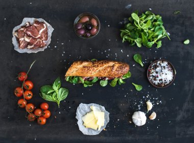 füme et, baget, fesleğen, roka, zeytin, kiraz domates, parmesan peyniri, sarımsak ve baharat siyah grunge arka plan üzerinde sandviç için malzemeler
