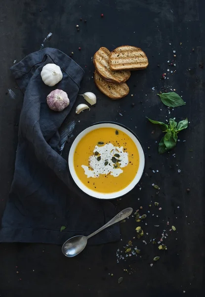 Pumpkin soup with cream, seeds, bread and fresh basil on grunge black background — Stock Image Pumpkin soup with cream, seeds, bread and fresh basil on grunge black background Royalty Free Stock Photos
