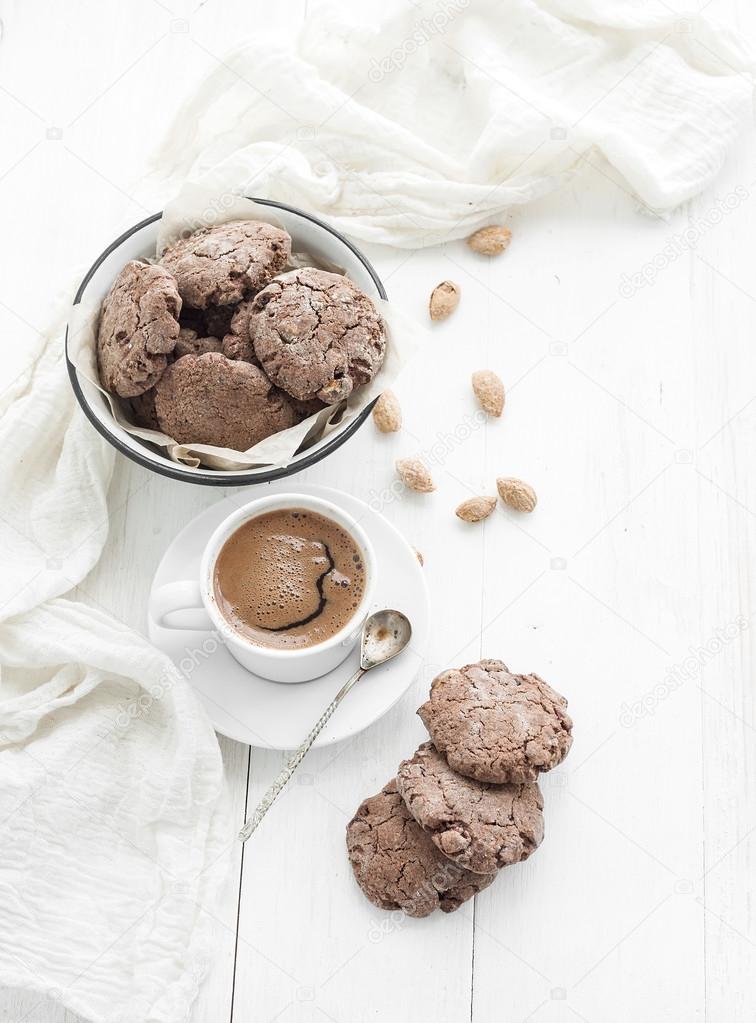 Chocolate cookies with almond and cranberries, cup of coffee, white wooden backdrop