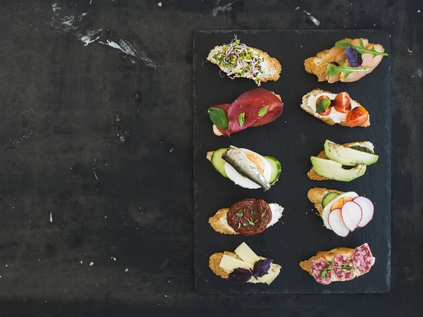 Міні сендвіч набір. Різноманітність маленьких бутербродів на чорному тлі — стокове фото
