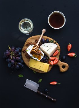 Meze seçimi peynir veya aperatif kümesi whine. Peynir, üzüm, pekan fındık, çilek ve bal siyah zemin üzerinde yuvarlak ahşap tahta üzerinde çeşitli