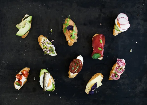 Міні сендвіч набір. Різноманітність маленьких бутербродів на чорному тлі — стокове фото