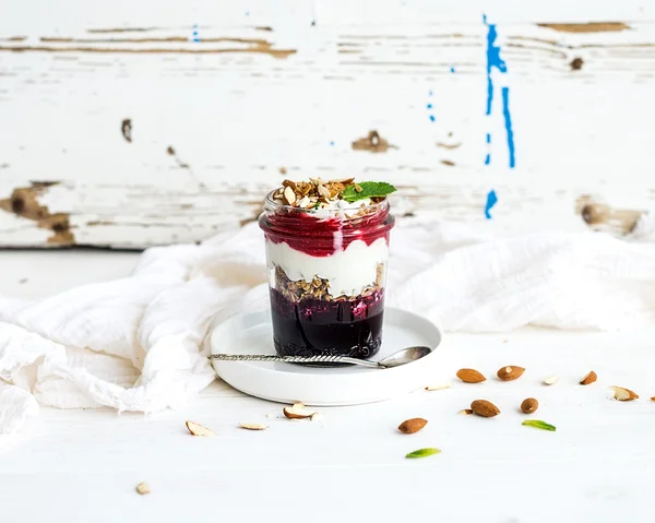Joghurt-Hafer-Müsli mit Beeren, Honig und Nüssen im Glas, rustikaler weißer Hintergrund — Stockfoto