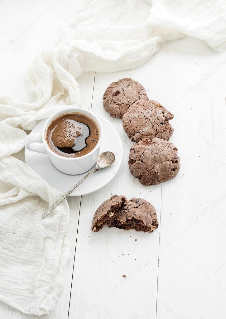 Chocolate cookies with almond and cranberries, cup of coffee, white wooden backdrop