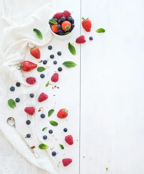 Berry frame with copy space on right. Strawberries, raspberries, blueberries and mint leaves, white wooden background — Stock Photo, Image