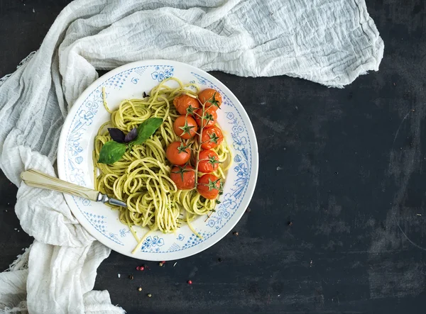 Makaron spaghetti z sosem pesto, bazylia, pieczone pomidory na rustykalne tabke drewniany ciemny tabela, widok z góry — Zdjęcie stockowe