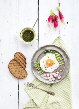 Healthy breakfast set. Fried egg with asparagus, radishes, green sauce and bread on vintage metal plate over white wooden backdrop