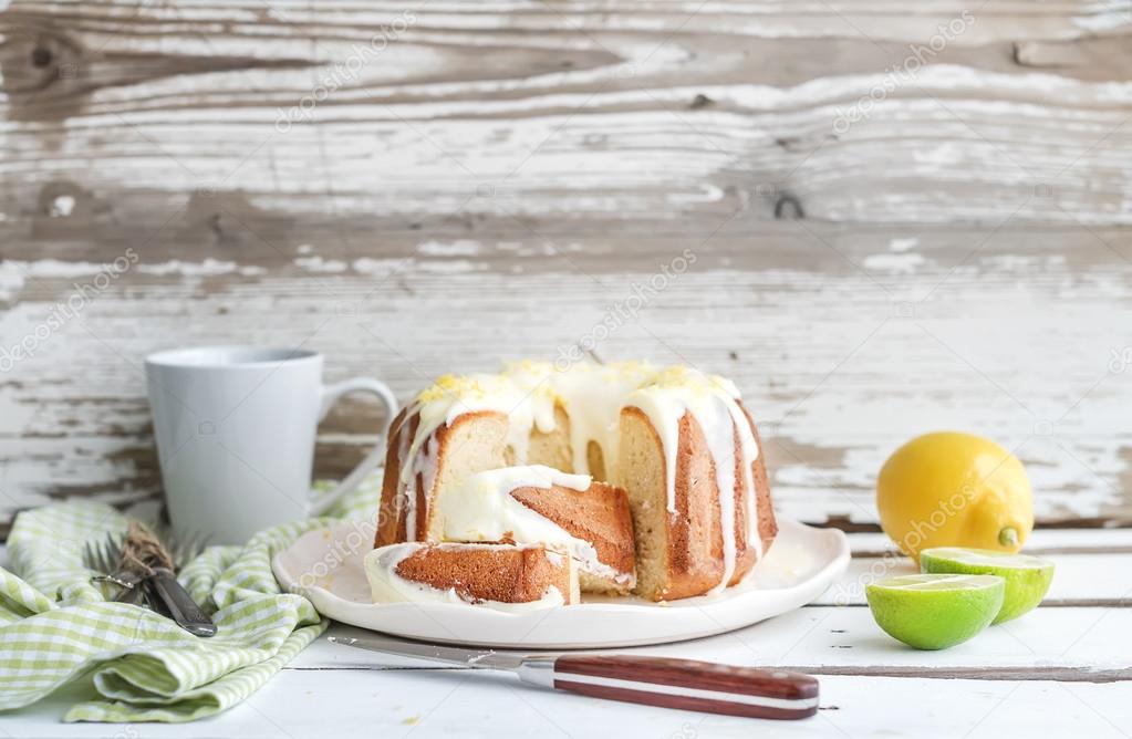 Moist lime and lemon bundt yoghurt cake, white rustic wooden  background.