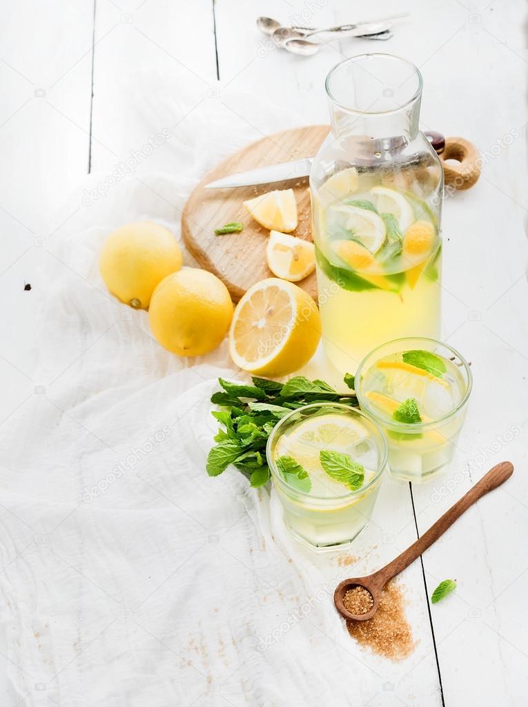 Fresh homemade lemonade with lemons and mint on white wooden background