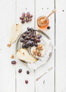 Camembert peyniri üzüm, ceviz, armut ve ballı beyaz rustik ahşap zemin üzerinde vintage metal plaka üzerinde