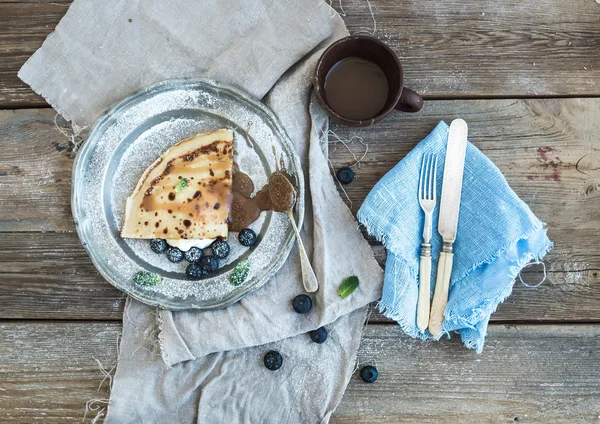 Frittella sottile o crespata con mirtillo fresco, panna, menta e salsa al caramello salata in piastra metallica vintage su uno sfondo di legno rustico — Foto Stock