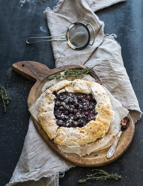 Tarte ou galette croustillante maison aux myrtilles, thym et crème glacée sur une planche de bois rustique sur fond sombre — Photo