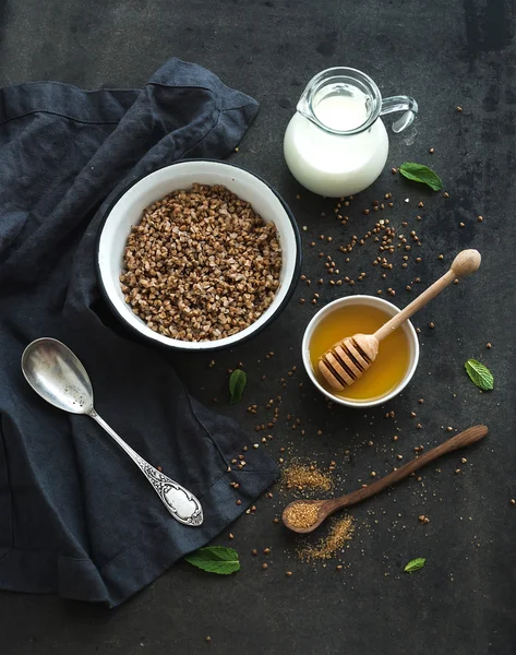 Rustic healthy breakfast set. Cooked buckwheat groats with milk and honey on dark grunge backdrop — Stock Photo, Image