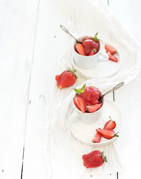 Gelato al sorbetto alla fragola con foglie di menta in tazze su fondo rustico in legno bianco, vista dall'alto — Foto Stock