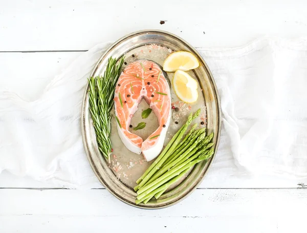 Raw salmon steak with asparagus, lemon, spices and rosemary on vintage silver tray over white wooden backdrop — Stok fotoğraf
