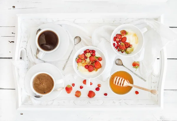 Healthy breakfast set. Yogurt, honey and wild srtawberry bowls with black coffee on serving tray over white rustic wooden backdrop — Stok fotoğraf