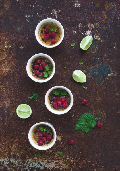 Brulees crema con frambuesas y menta en cuencos blancos sobre fondo de metal grunge. Vista superior — Foto de Stock