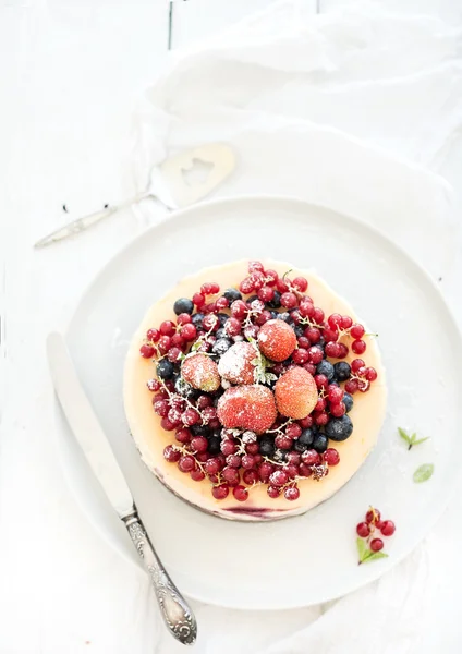 Сирник зі свіжими садовими ягодами зверху над білою дерев'яною поверхнею столу. Вибірковий фокус — стокове фото