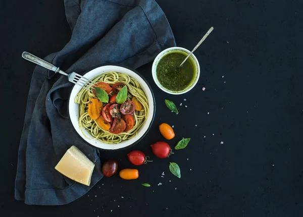 Spaghettis aux pâtes avec sauce pesto, basilic, tomates cerises rôties lentement dans un bol en métal rustique sur fond de grunge foncé, vue sur le dessus — Photo