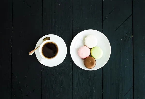 Macaron cookies, cup of espresso over black wooden backdrop — ストック写真