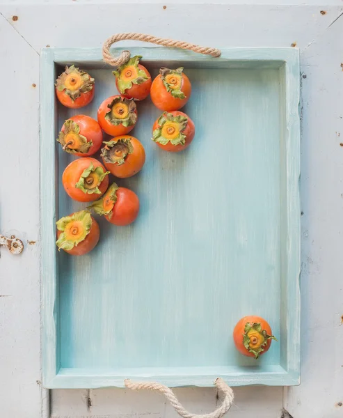 Ripe fresh persimmons on blue — Stockfoto