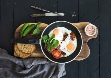 Pan of fried eggs, bacon, tomatoes