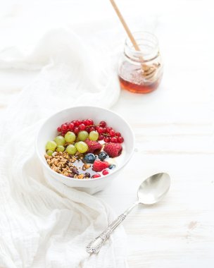 Bowl of oat granola with yogurt, fresh berries and honey.
