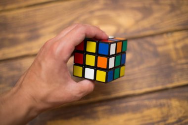 Elleri renkli bir yapboz. Rubik küpü 3 'er 3' er tahta bir masada yatıyor.