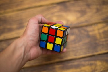 Elleri renkli bir yapboz. Rubik küpü 3 'er 3' er tahta bir masada yatıyor.