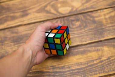 Elleri renkli bir yapboz. Rubik küpü 3 'er 3' er tahta bir masada yatıyor.
