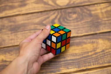 Elleri renkli bir yapboz. Rubik küpü 3 'er 3' er tahta bir masada yatıyor.