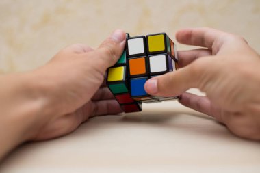 Elleri renkli bir yapboz. Rubik küpü 3 'er 3' er tahta bir masada yatıyor.