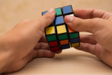 Elleri renkli bir yapboz. Rubik küpü 3 'er 3' er tahta bir masada yatıyor.