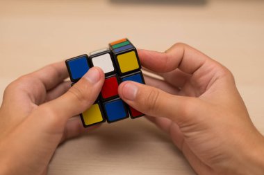 Elleri renkli bir yapboz. Rubik küpü 3 'er 3' er tahta bir masada yatıyor.