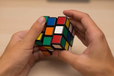 Elleri renkli bir yapboz. Rubik küpü 3 'er 3' er tahta bir masada yatıyor.