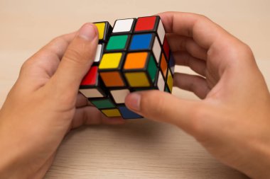 Elleri renkli bir yapboz. Rubik küpü 3 'er 3' er tahta bir masada yatıyor.