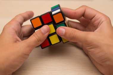 Elleri renkli bir yapboz. Rubik küpü 3 'er 3' er tahta bir masada yatıyor.