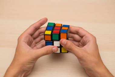 Elleri renkli bir yapboz. Rubik küpü 3 'er 3' er tahta bir masada yatıyor.