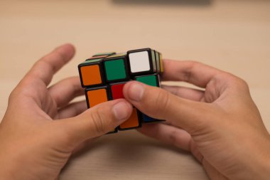 Elleri renkli bir yapboz. Rubik küpü 3 'er 3' er tahta bir masada yatıyor.