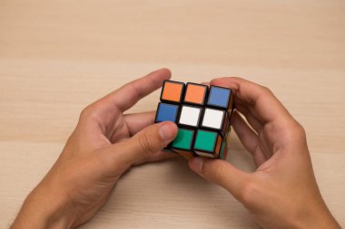 Elleri renkli bir yapboz. Rubik küpü 3 'er 3' er tahta bir masada yatıyor.