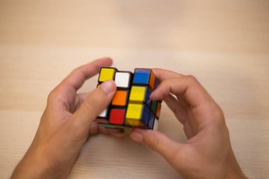 Elleri renkli bir yapboz. Rubik küpü 3 'er 3' er tahta bir masada yatıyor.