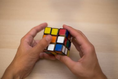 Elleri renkli bir yapboz. Rubik küpü 3 'er 3' er tahta bir masada yatıyor.