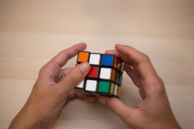 Elleri renkli bir yapboz. Rubik küpü 3 'er 3' er tahta bir masada yatıyor.