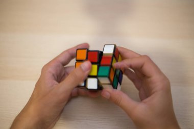 Elleri renkli bir yapboz. Rubik küpü 3 'er 3' er tahta bir masada yatıyor.