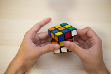 Elleri renkli bir yapboz. Rubik küpü 3 'er 3' er tahta bir masada yatıyor.
