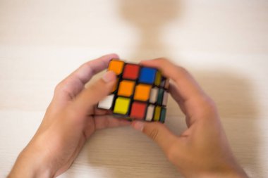 Elleri renkli bir yapboz. Rubik küpü 3 'er 3' er tahta bir masada yatıyor.