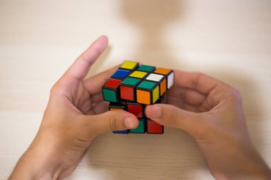 Elleri renkli bir yapboz. Rubik küpü 3 'er 3' er tahta bir masada yatıyor.